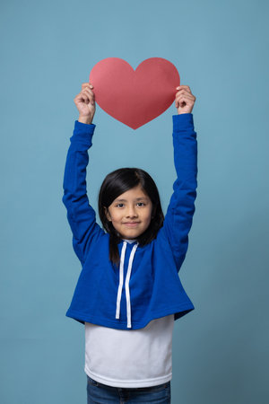 Mexican little girl holding a red heart self love, valentine's day conceptの写真素材