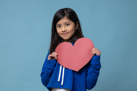 Mexican little girl holding a red heart self love, valentine's day conceptの写真素材