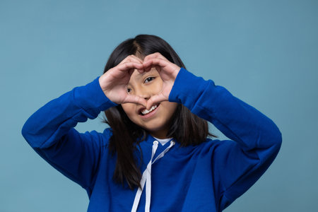 Mexican little girl doing hear sign with her handsの写真素材