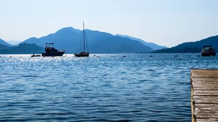 Landscape of sea and mountains with the boats and the jetty.の写真素材