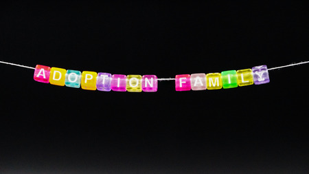 "Adoption family" composed of multicolored plastic blocks suspended on a thread.の写真素材