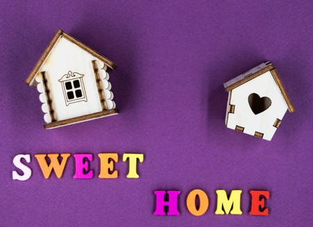 The phrase "Sweet home" laid out on a pink background with two toy wooden houses.の写真素材