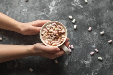 Hands holding a white cup of hot cocoa drink with marshmallows with copy spaceの写真素材