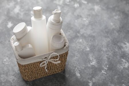 A basket full of white plastic cosmetic bottles on a gray background with copy spaceの写真素材