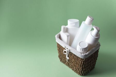 A basket full of white plastic cosmetic bottles on a light green backgroundの写真素材