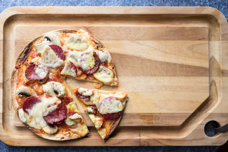 Sliced salami pizza with mozzarella cheese, white mushroom and srirachaの写真素材