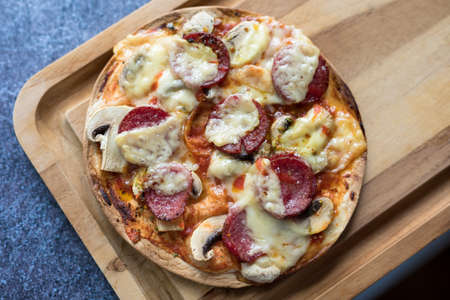 Sliced salami pizza with mozzarella cheese, white mushroom and srirachaの写真素材