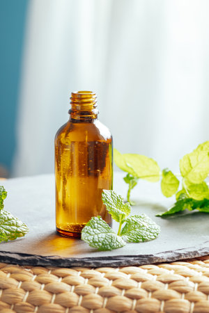 Mint or peppermint essential oil in a glass bottle used as an alternative medicine in aromatherapy or diluted in a carrier oil directly on skinの写真素材