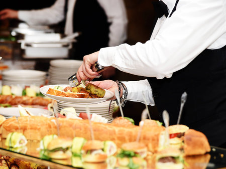 Waiter carrying plates with potato vegetable dish on some reception event, party or wedding partyの写真素材