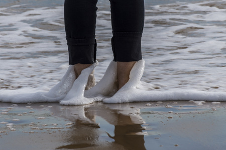 sea waves bathing a woman's feet on the beach. Guardamar del Segura, Spainの写真素材