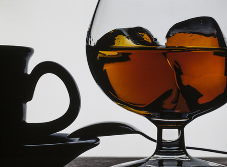 Cognac glass with ice and coffee cup. On white backgroundの写真素材