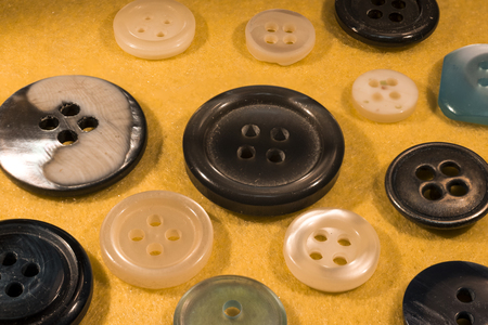 detail of several buttons for clothes, on yellow velvet backgroundの写真素材