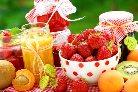 various fruits preserves in jars and fresh fruits on garden tableの写真素材