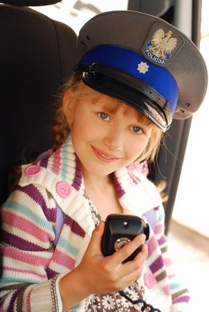 young girl wearing polish police hat holding radio in carの写真素材