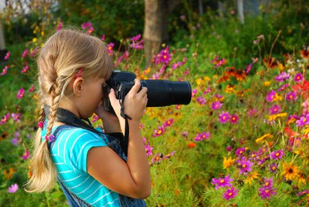 young girl taking photos by professional digital camera in autumn garden