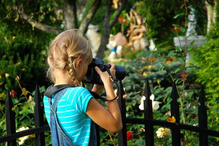 young girl taking photos by professional digital camera in autumn gardenの写真素材