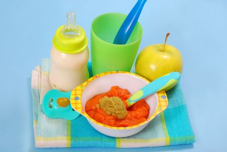 bowl of fresh grated carrot and green peas puree and bottle of milk as homemade baby foodの写真素材