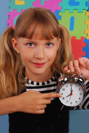 schoolgirl pointing retro alarm clock and showing that it`s time for schoolの写真素材