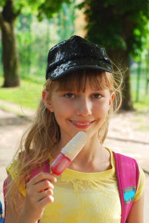 young girl eating ice cream outdoor after schoolの写真素材