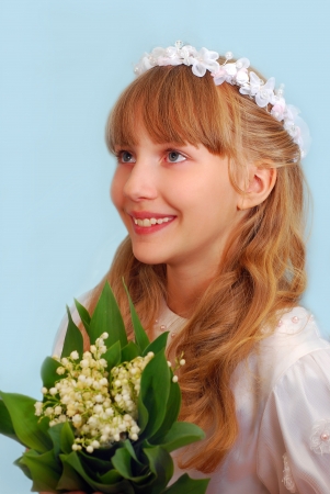 portrait of happy girl going to the first holy communion and posing in studio with bunch of lily of the valley flowers の写真素材