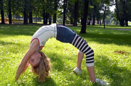 young girl  exercising in bridge pose in the parkの写真素材