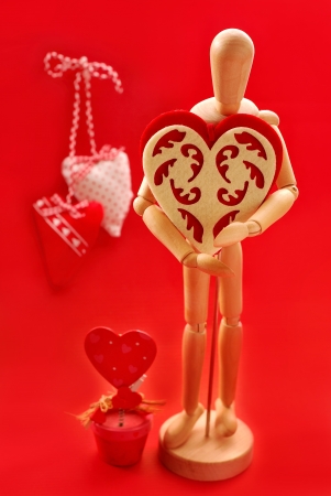 wooden model holding big felt heart as gift for valentineの写真素材