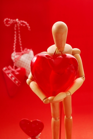 wooden model holding big plastic heart as gift for valentineの写真素材