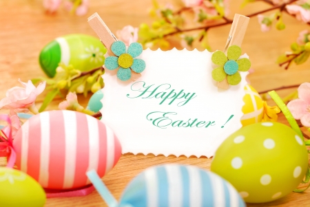 colorful painted easter eggs and greetings card on wooden background