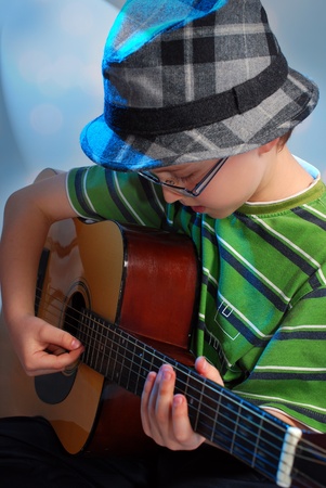 young boy in hat playing the classical guitar on stageの写真素材
