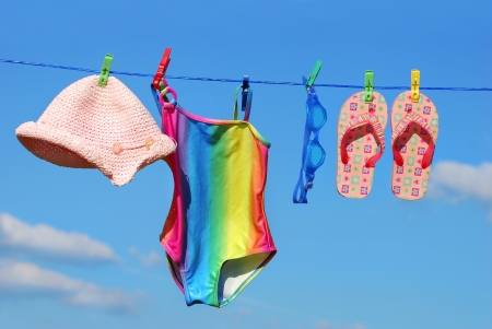 Summer holidays accessories hanging on clothesline against blue skyの写真素材