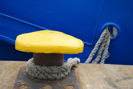 yellow mooring bollard with rope securing ship in the portの写真素材