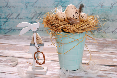 beautiful easter decoration with wooden bunny and nest with eggs in pastel colors