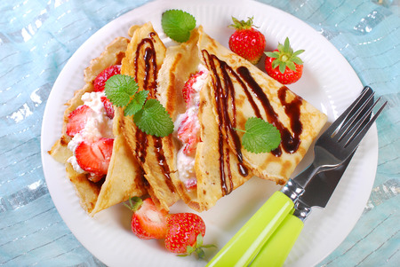 pancakes filled with cottage cheese,cream and fresh strawberries poured chocolate sauceの写真素材
