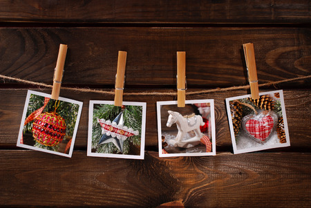 four vintage style christmas  photos hanging on rope with bamboo clothespins against old wooden backgroundの写真素材