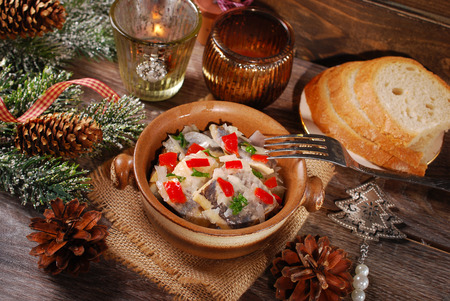 herring salad with onion,red pepper and oil for christmas served in rustic style on wooden tableの写真素材