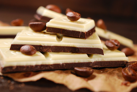 pieces of black and white coffee chocolate bar with seeds on wooden table