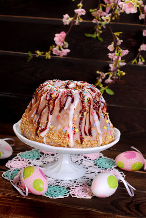 easter ring cake with icing ,chocolate glaze and colorful sprinkles on wooden background