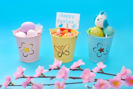 easter decoration with eggs  in three pastel color buckets on blue background