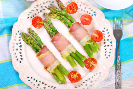 plate with green asparagus wrapped in ham and mozzarella cheeseの写真素材