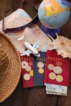 summer holiday traveling concept with passports,money,maps,airplane and straw hat on wooden backgroundの写真素材