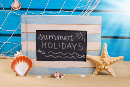 seaside background and marine wooden frame with chalk written text on blackboard standing on beach sandの写真素材
