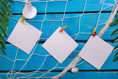 summer holiday background with blank cards pinned to the fishing net hanging on blue wooden planksの写真素材