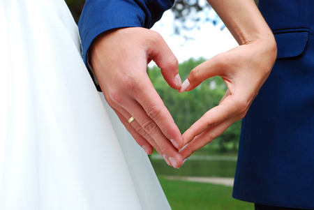 the bride and groom hands forming a heart shape symbol of love