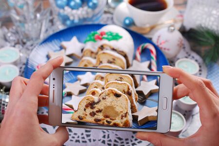 Hands taking a photo of Christmas stollen cake to a smartphone