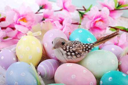 easter background with a bird sitting on pastel color eggs painted with dots