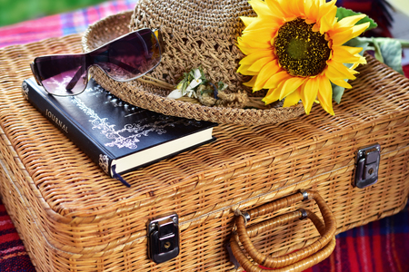 summer still life with retro wicker suitcase,straw hat,diary,sunflower and sunglasses on the grassの写真素材