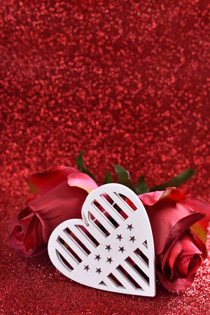white wooden heart and two roses for valentines on red glitter background  with copy space for own textの写真素材