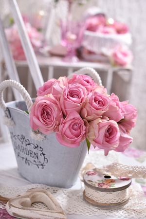 shabby chic style interior decoration with bunch of pink roses on the chairの写真素材