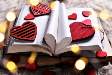 Valentine's day concept with opened book of love with sheets in the shape of a heart and red wooden heartsの写真素材