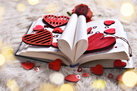 Valentine's day concept with opened book of love in the shape of heart and red wooden heartsの写真素材